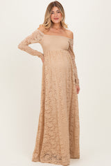 woman wearing a beige lace off-shoulder maternity gown with long sleeves and a visible baby bump