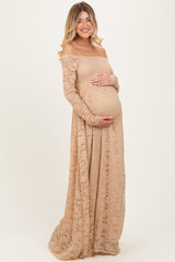 woman wearing a nude off-the-shoulder lace maternity gown and holding her baby bump