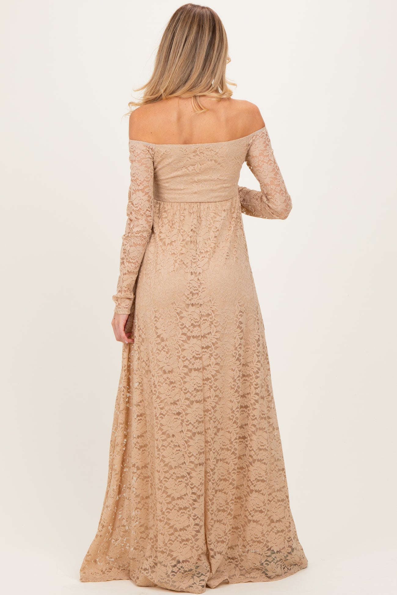 woman wearing a long sleeve light beige lace maternity dress with an off-shoulder design and flowing skirt