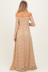 woman wearing a long sleeve light beige lace maternity dress with an off-shoulder design and flowing skirt