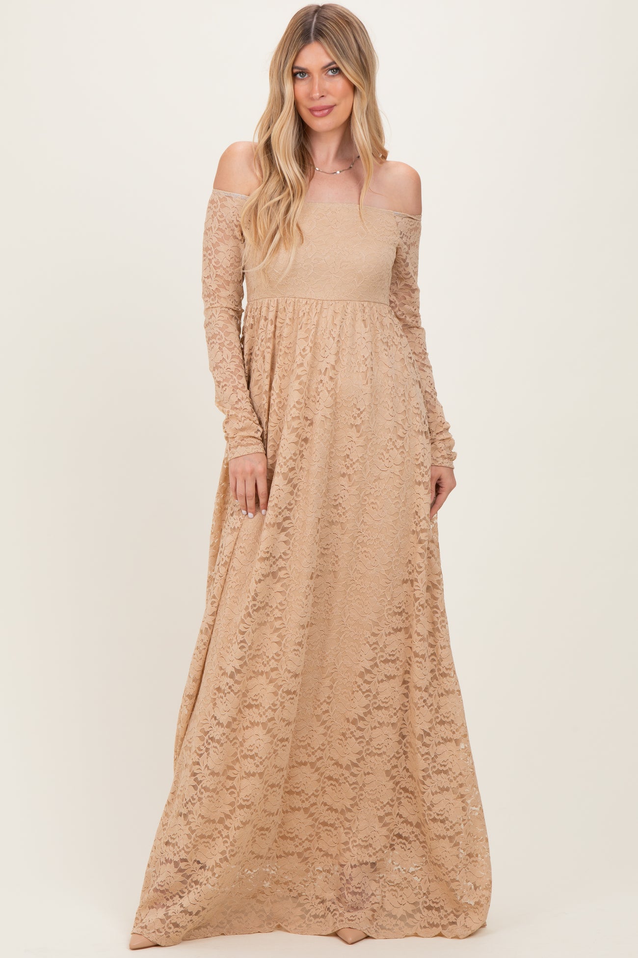 woman wearing a beige off-the-shoulder lace maxi dress with long sleeves and a flowy skirt
