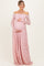 woman wearing a light pink off-the-shoulder lace maternity gown and holding her baby bump