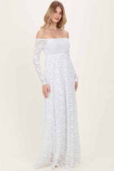 woman wearing a white off-the-shoulder lace maxi dress with long sleeves and a flowy skirt