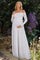 woman wearing a white lace off-shoulder maternity dress and holding her baby bump in a garden setting