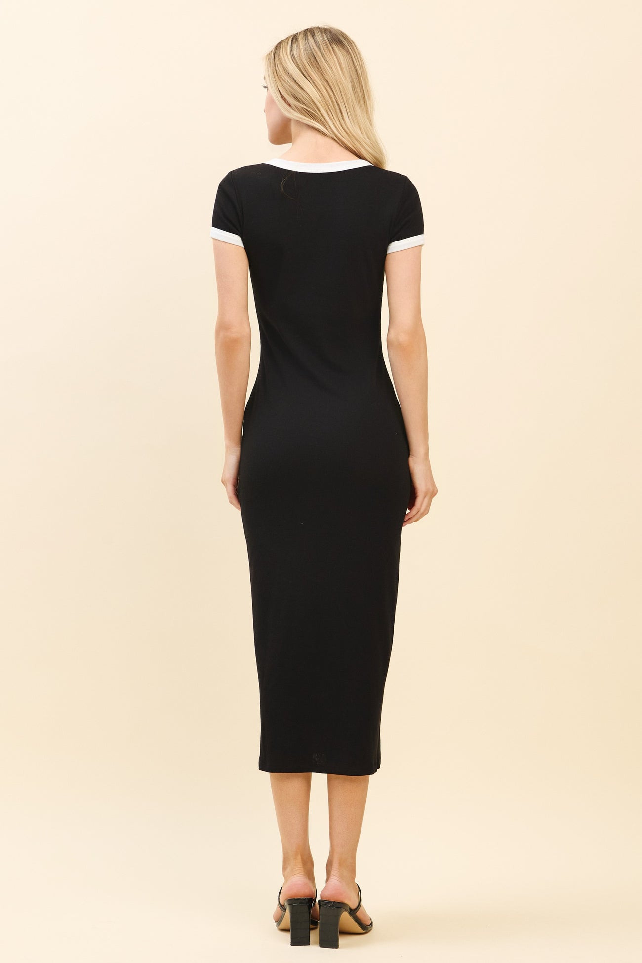 woman wearing a black midi dress with white trim on the sleeves, showing the back view