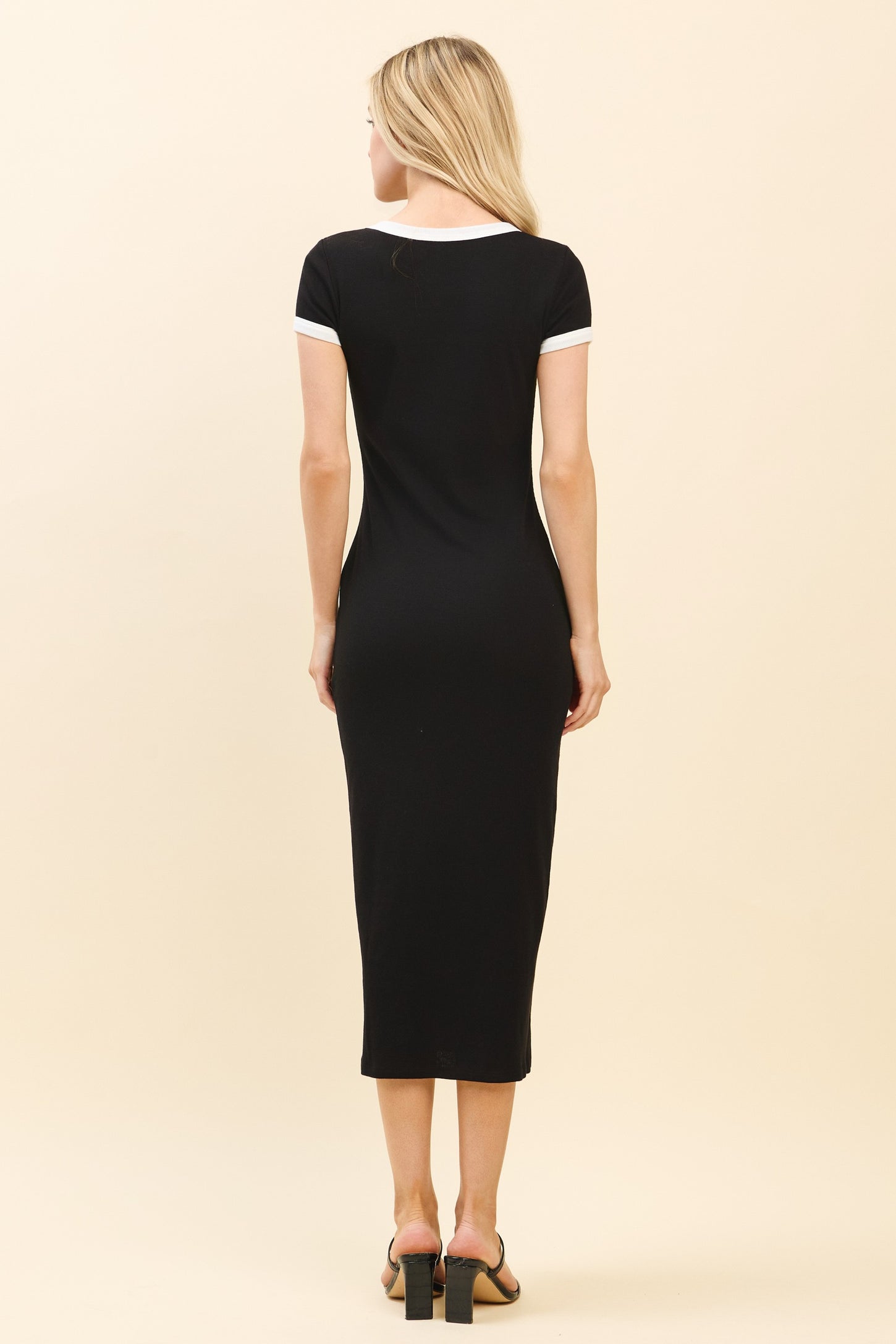 woman wearing a black midi dress with white trim on the sleeves, showing the back view