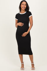 woman wearing a black maternity dress with short sleeves and white trim, holding her baby bump