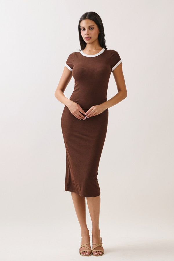 woman wearing a brown ribbed midi dress with white trim and short sleeves, standing against a neutral background