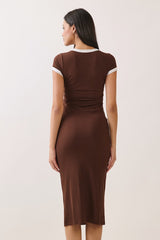 woman wearing a brown fitted dress with short sleeves and a white trim, showing the back view