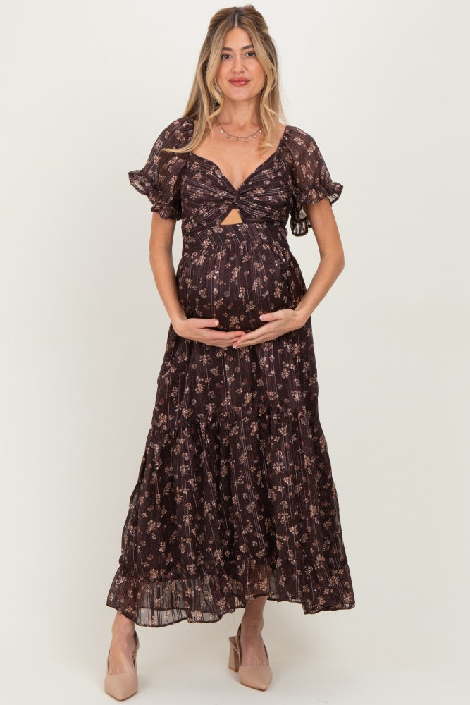 woman wearing a dark floral print maternity dress with a twist front and ruffled sleeves, holding her baby bump
