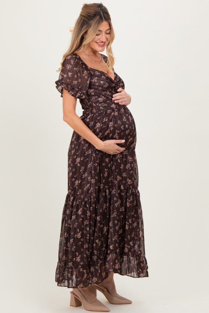 woman wearing a dark floral maternity maxi dress and cradling her baby bump