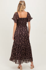woman wearing a black floral maternity maxi dress with a smocked bodice and ruffled hem, showing a baby bump