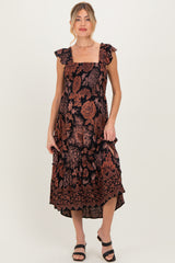 woman wearing a black floral maternity dress with ruffled straps and a midi length, showcasing a baby bump