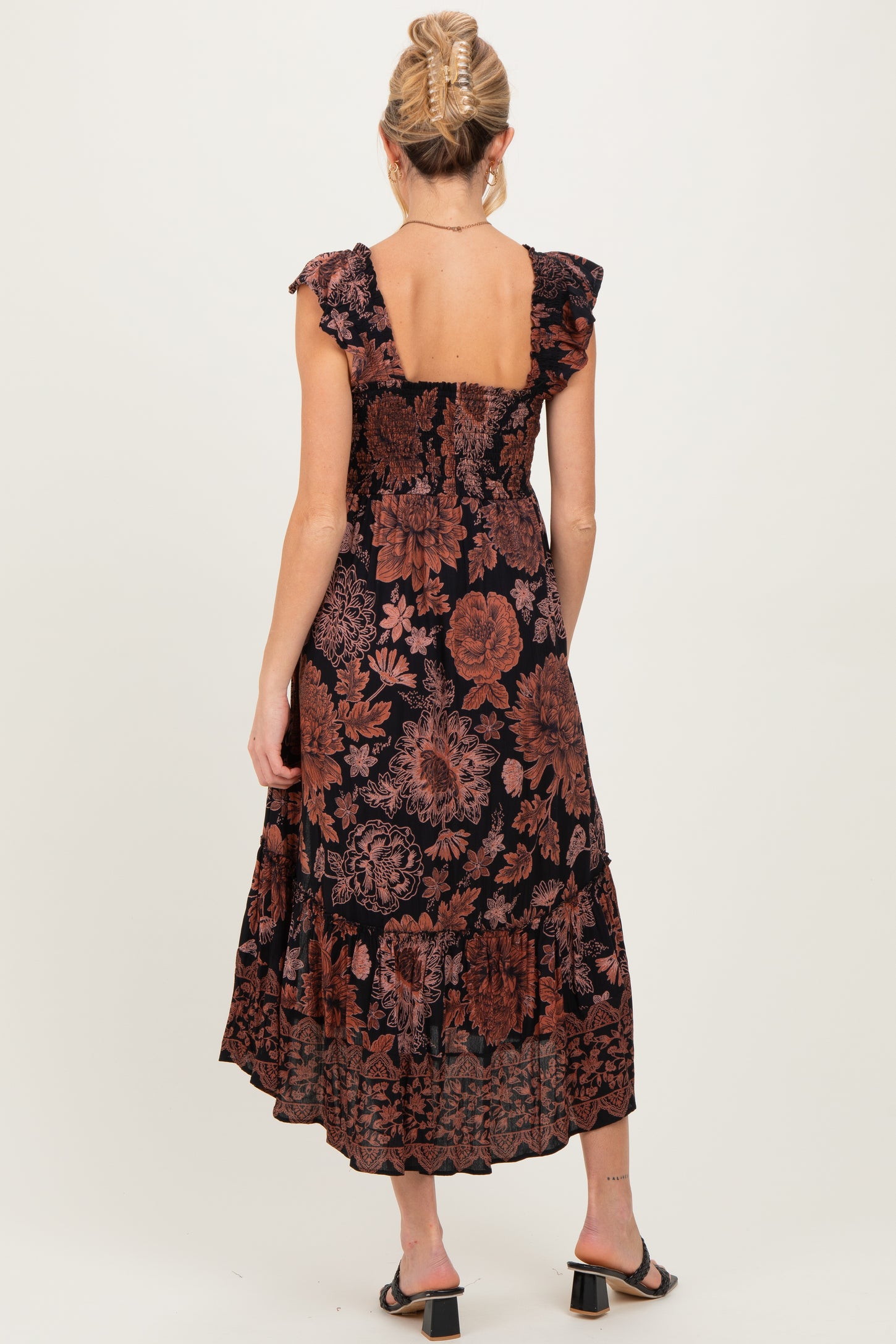 woman wearing a black floral maternity maxi dress with ruffle sleeves and a smocked back, showing a baby bump