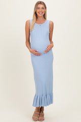 woman wearing a light blue ribbed maternity dress with a ruffled hem and holding her baby bump