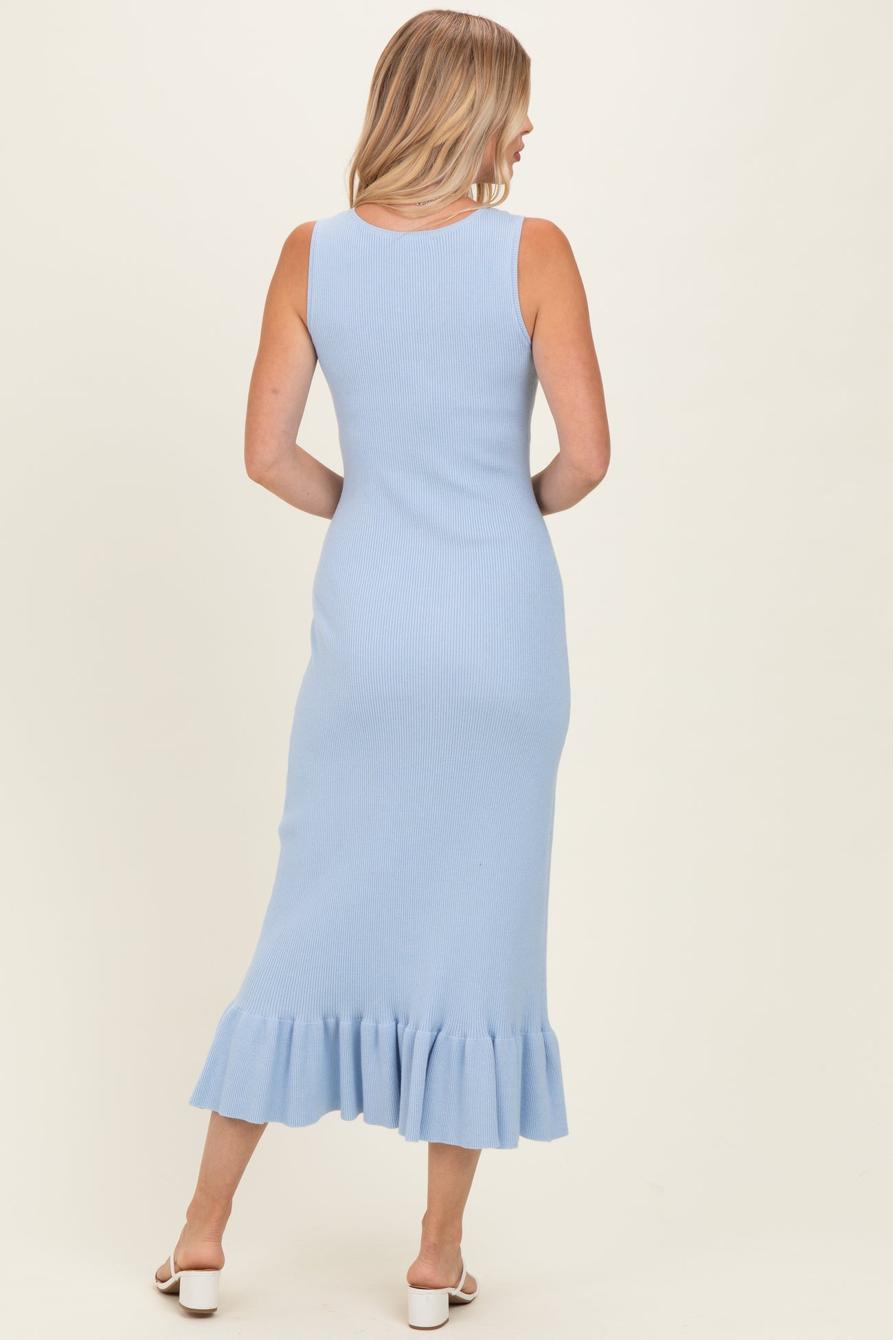 woman wearing a light blue ribbed maxi dress with a ruffled hem and a sleeveless design, seen from the back