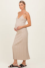 woman wearing a beige ribbed maternity dress with a v-neckline and holding her baby bump