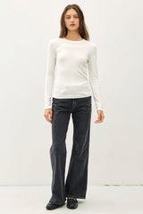 woman wearing a white long sleeve fitted top and black flared jeans