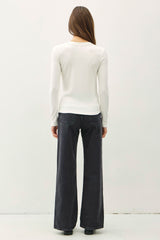 woman wearing a white long sleeve top and black wide-leg jeans, viewed from the back