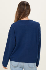 woman wearing a navy blue oversized maternity sweater, seen from the back, paired with light blue jeans