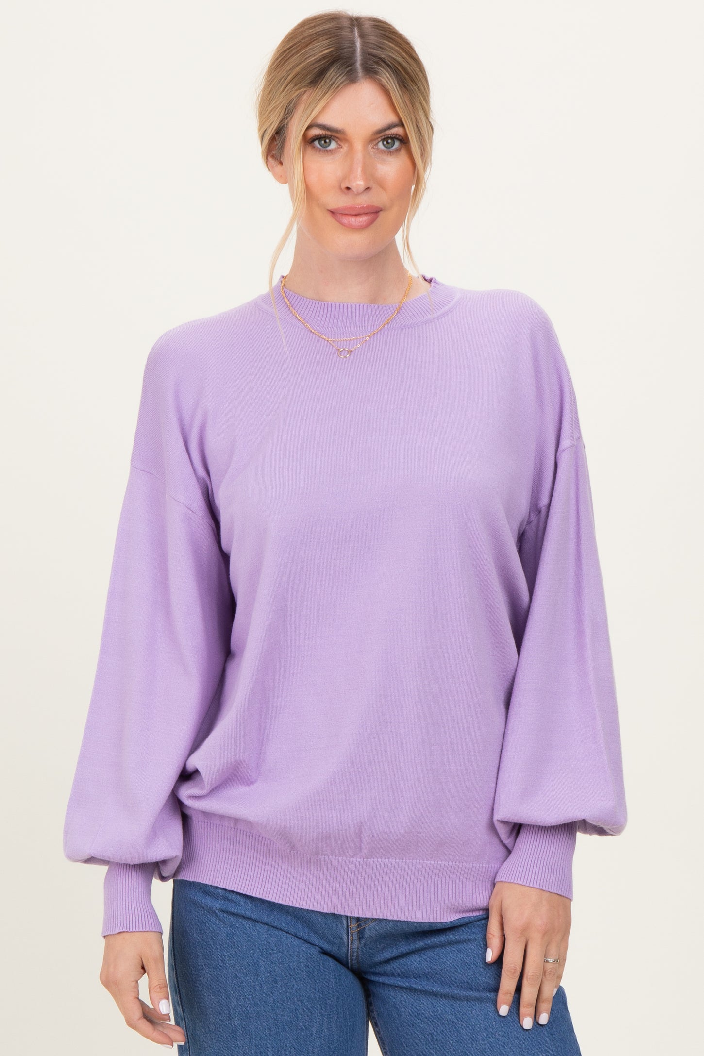 woman wearing a light purple oversized sweater with balloon sleeves and a crew neckline paired with blue jeans