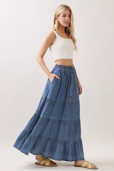 woman wearing a white ribbed crop top and a denim tiered maxi skirt with pockets and a drawstring waist