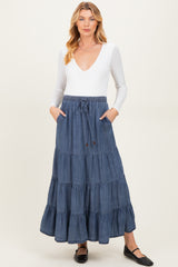 woman wearing a white long sleeve v-neck maternity top and a blue tiered maxi skirt with pockets