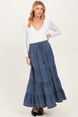 woman wearing a white long sleeve v-neck top and a dark denim tiered maxi skirt, showcasing her baby bump