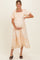 woman wearing a light peach and white gingham maternity dress with puff sleeves and a tiered hem, holding her baby bump