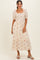 woman wearing a cream puff sleeve midi dress with floral print and ruffle hem, paired with gray slip-on mules