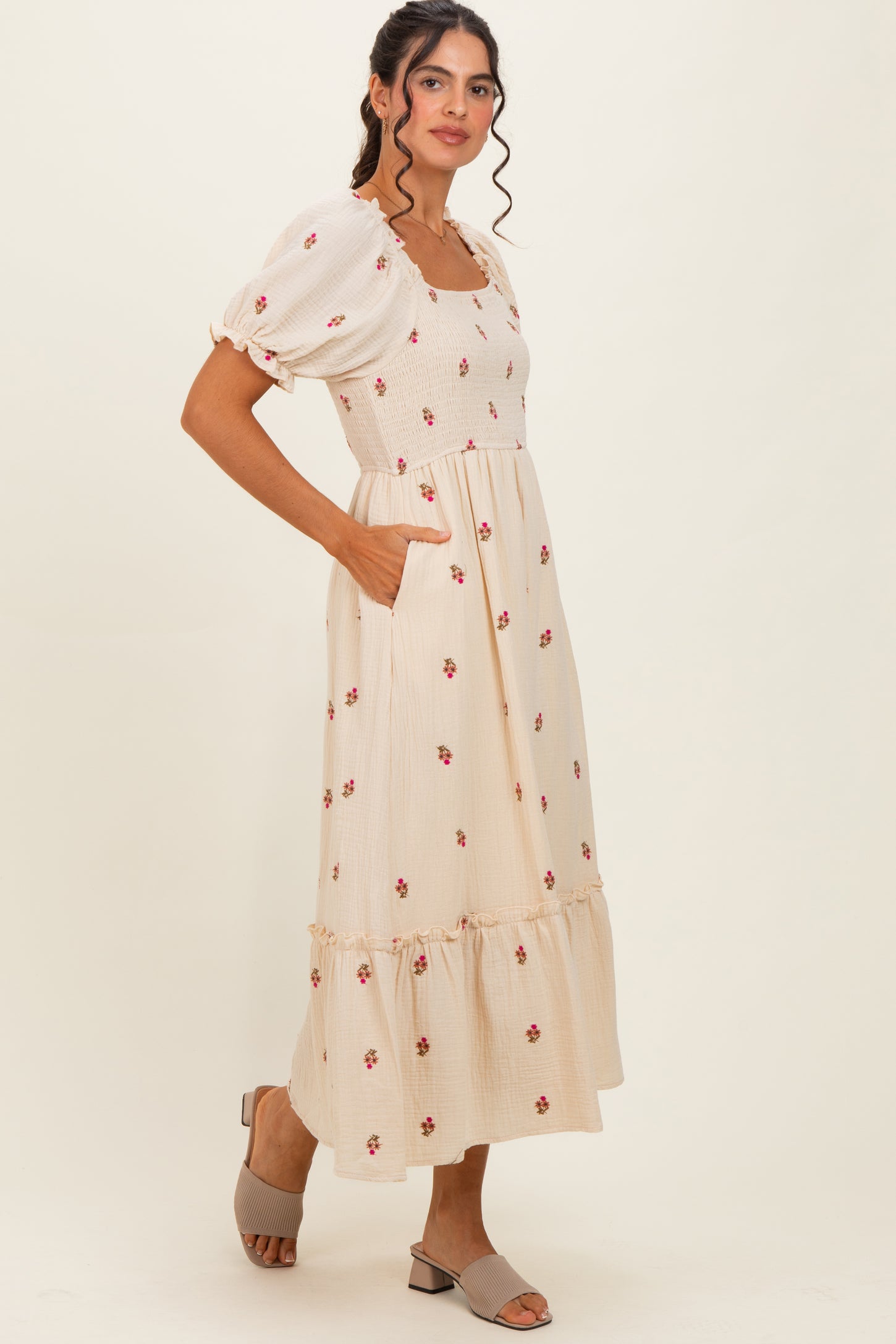 woman wearing a cream floral maxi dress with puff sleeves and pockets, styled with open-toe sandals