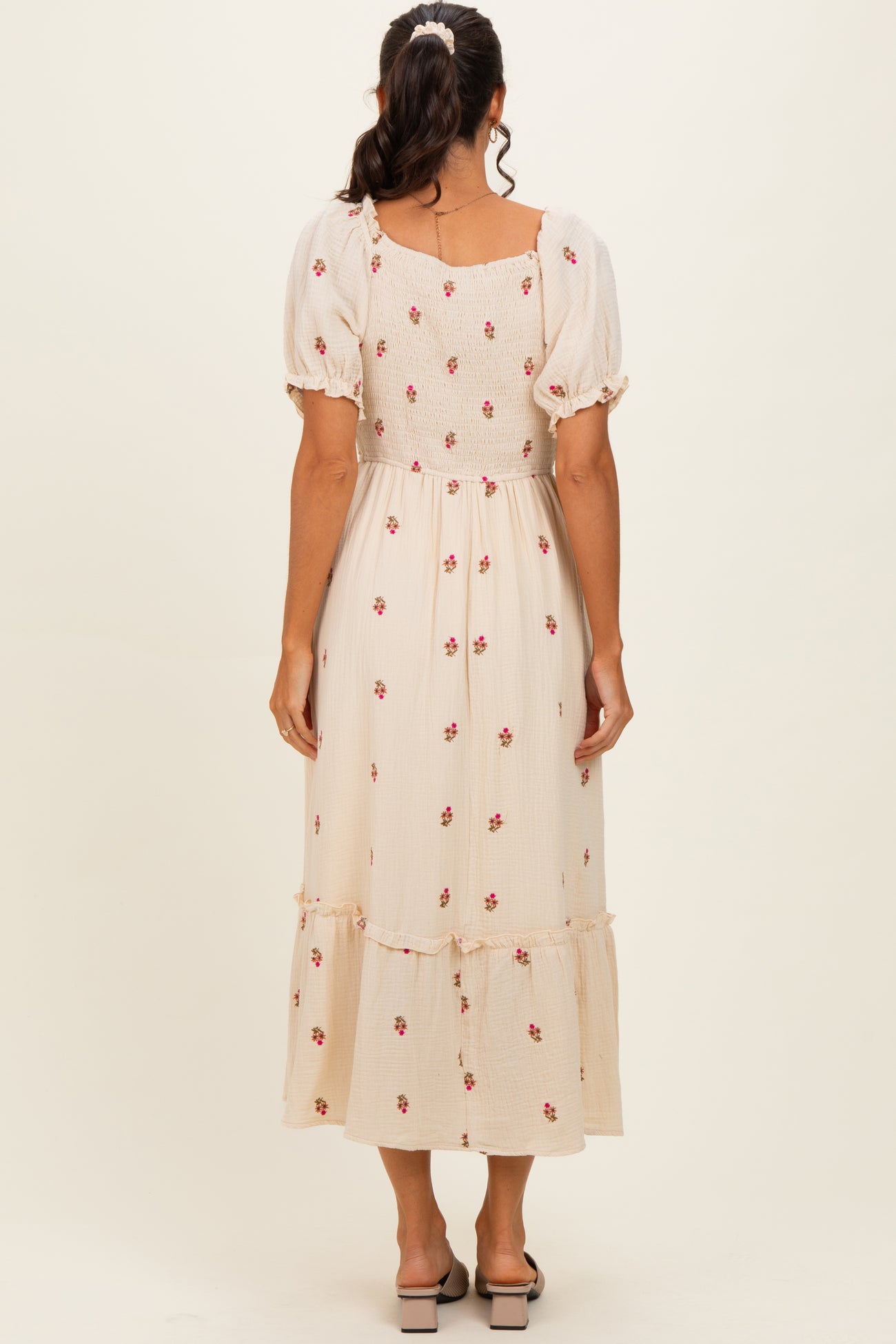 woman wearing a beige floral midi dress with puff sleeves and a tiered hem, viewed from the back