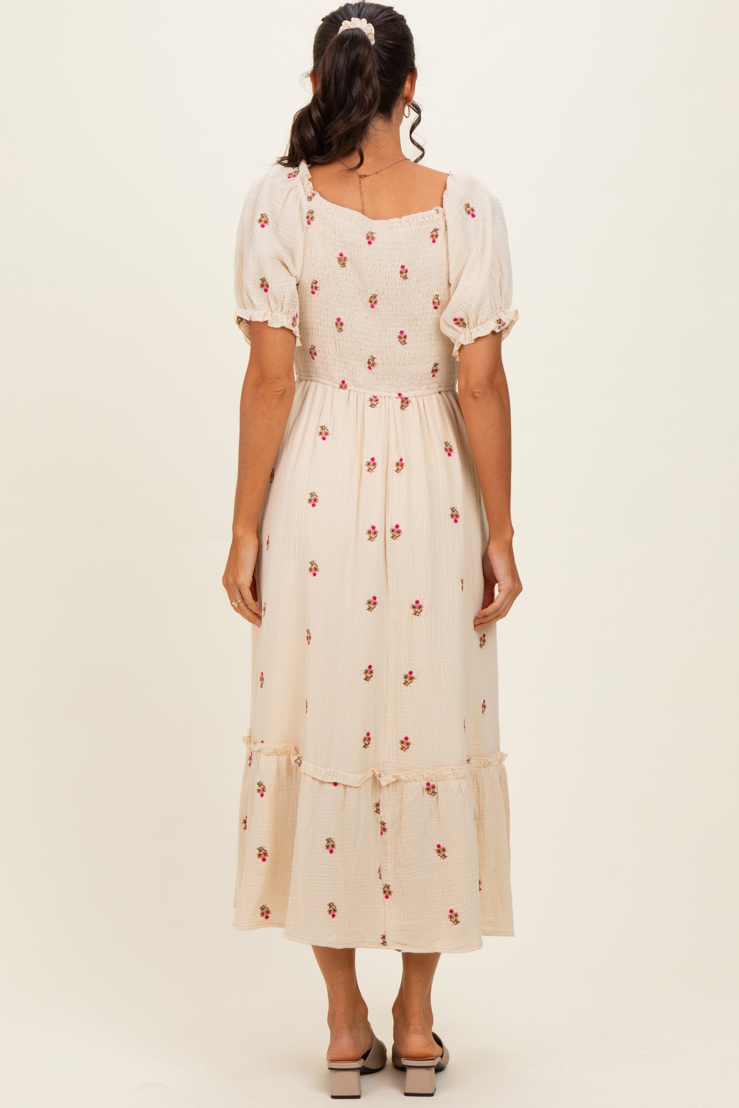 woman wearing a beige floral midi dress with puff sleeves and a tiered hem, viewed from the back