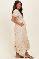 woman wearing a cream floral maternity dress with puff sleeves and a tiered skirt, showcasing her baby bump