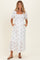 woman wearing a white floral maternity maxi dress with puff sleeves and pockets, showcasing her baby bump