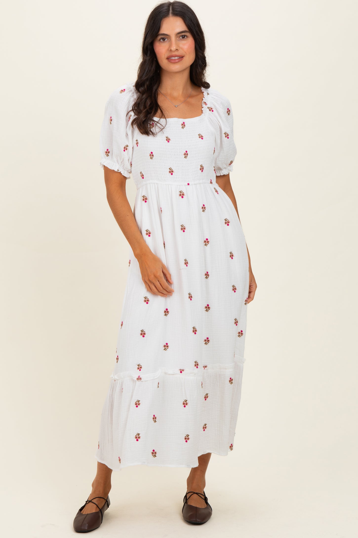 woman wearing a white maxi dress with floral embroidery and short puff sleeves