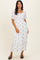 woman wearing a white maxi dress with floral embroidery and short puff sleeves