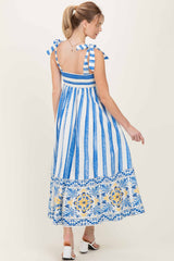 woman wearing a blue and white striped maxi dress with ruffled straps and floral border detail, seen from the back