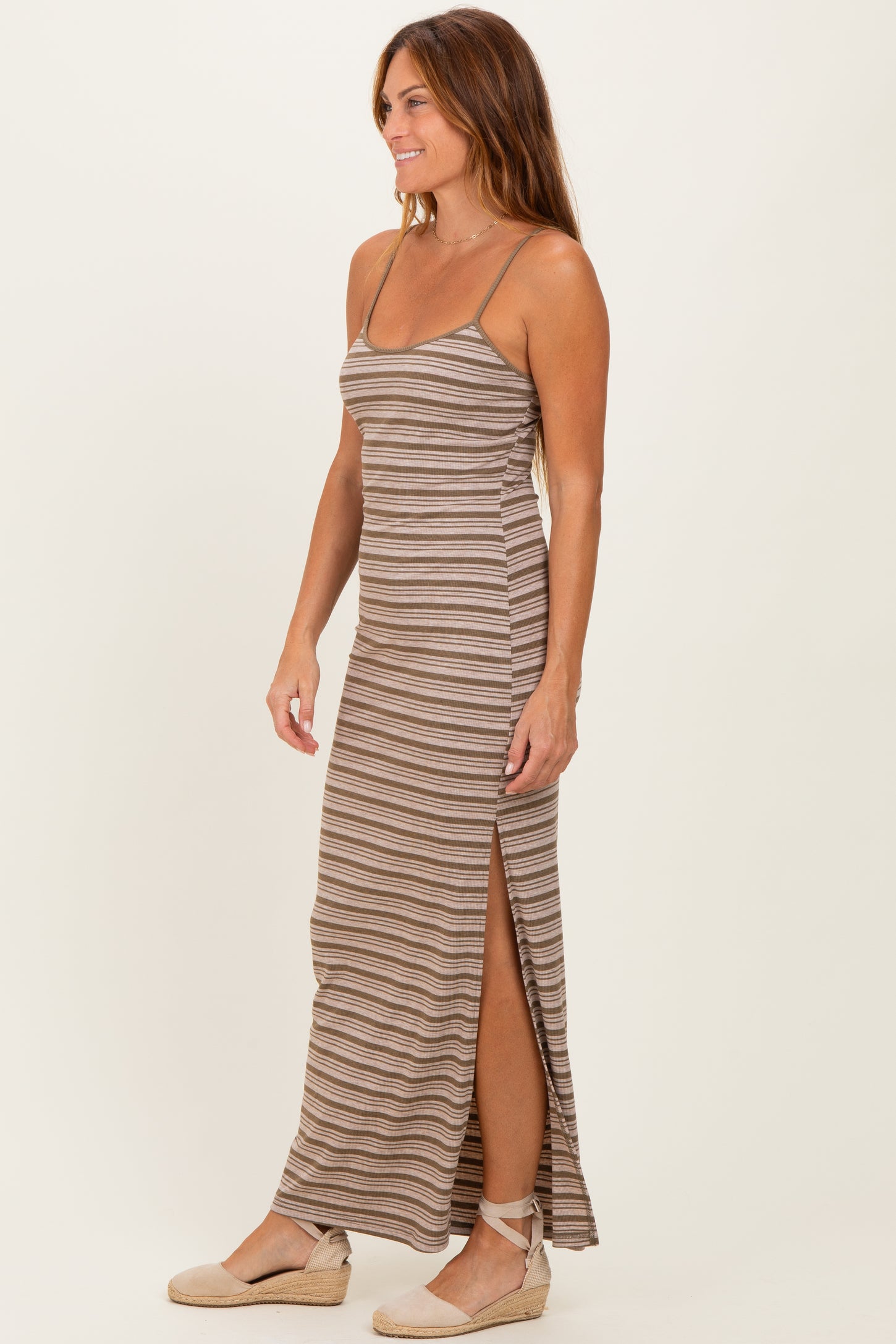 woman wearing a brown striped maxi dress with side slits and spaghetti straps