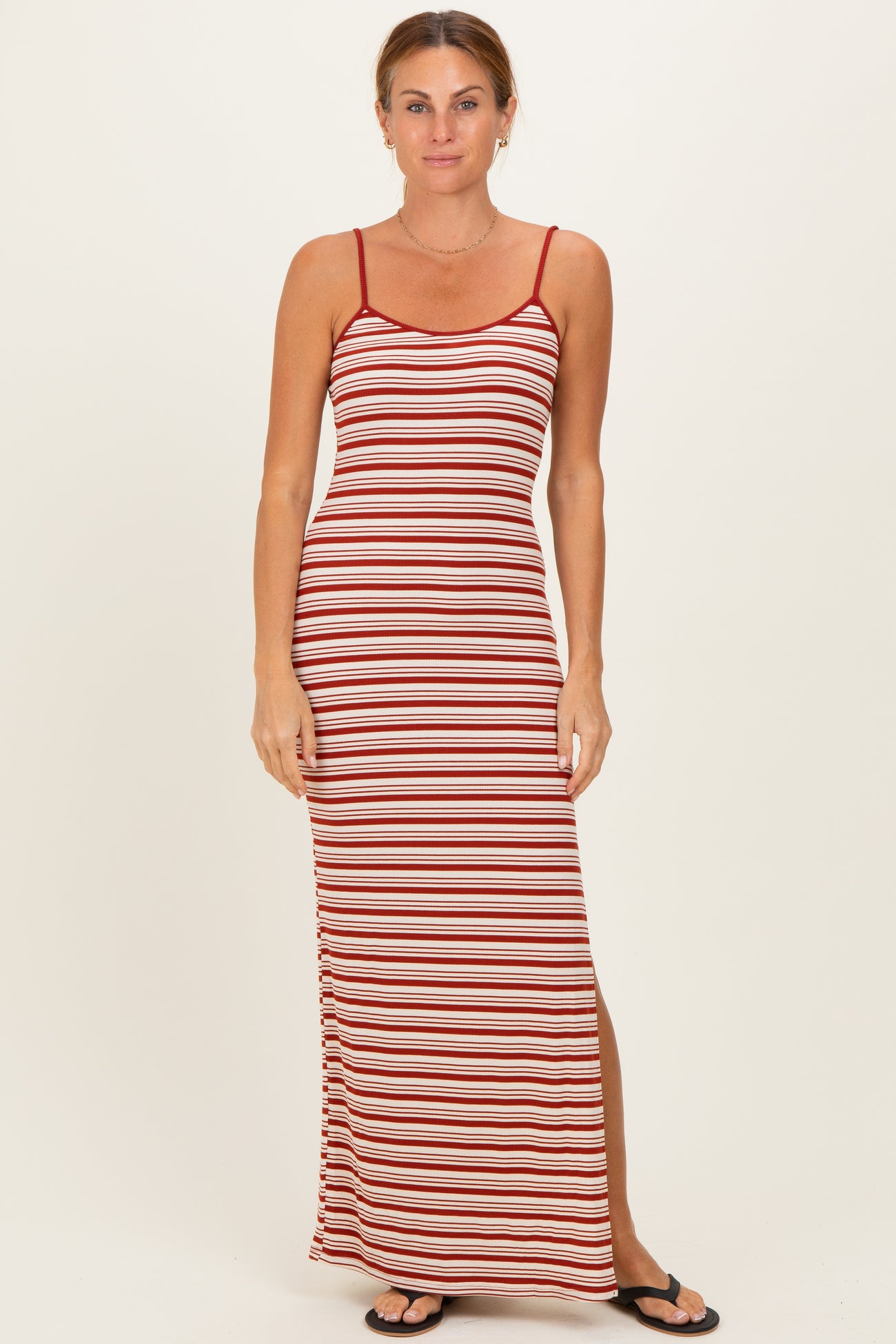woman wearing a red and white striped maxi dress with thin straps and a side slit