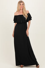 woman wearing a black off-the-shoulder maxi dress with ruffled sleeves and a fitted waistline