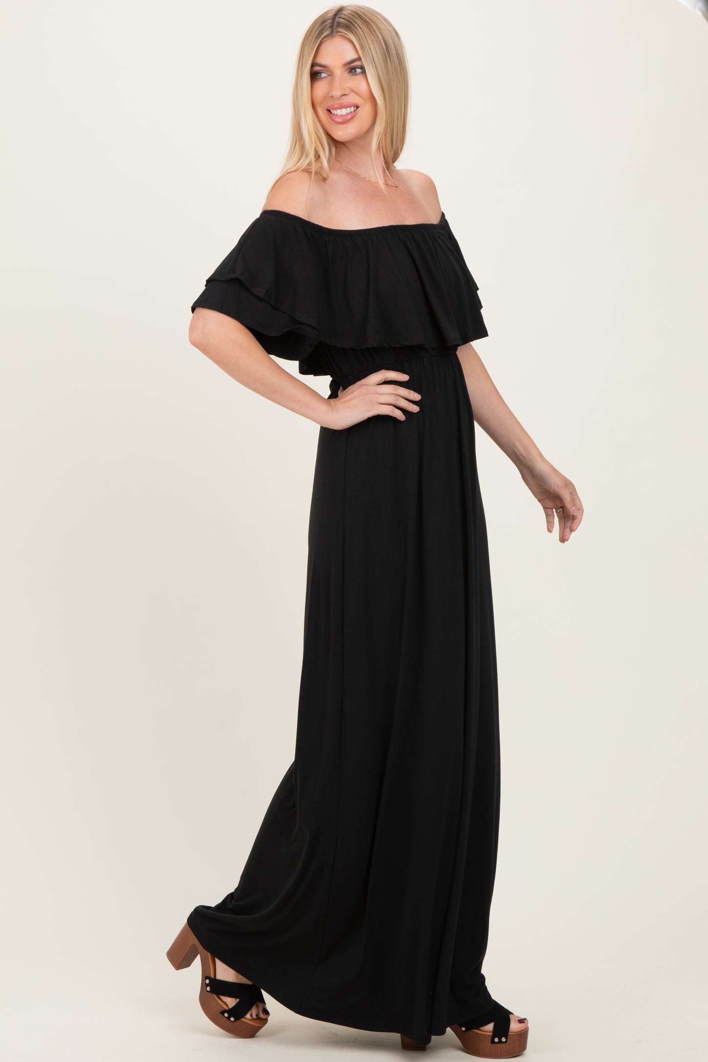 woman wearing a black off-the-shoulder maxi dress with ruffled sleeves and standing in profile