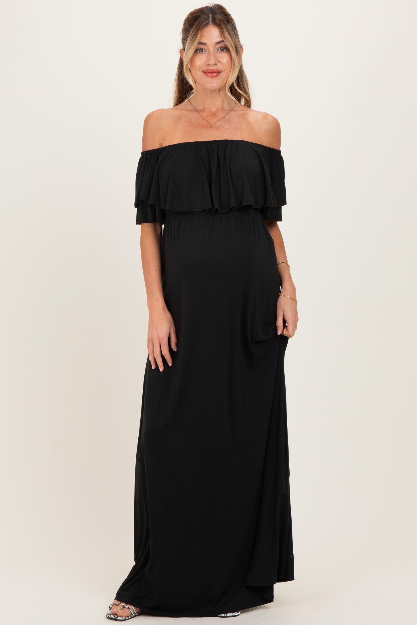 woman wearing a black off-shoulder maternity maxi dress showcasing her baby bump