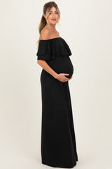 woman wearing a black off-the-shoulder maternity maxi dress, gently cradling her baby bump