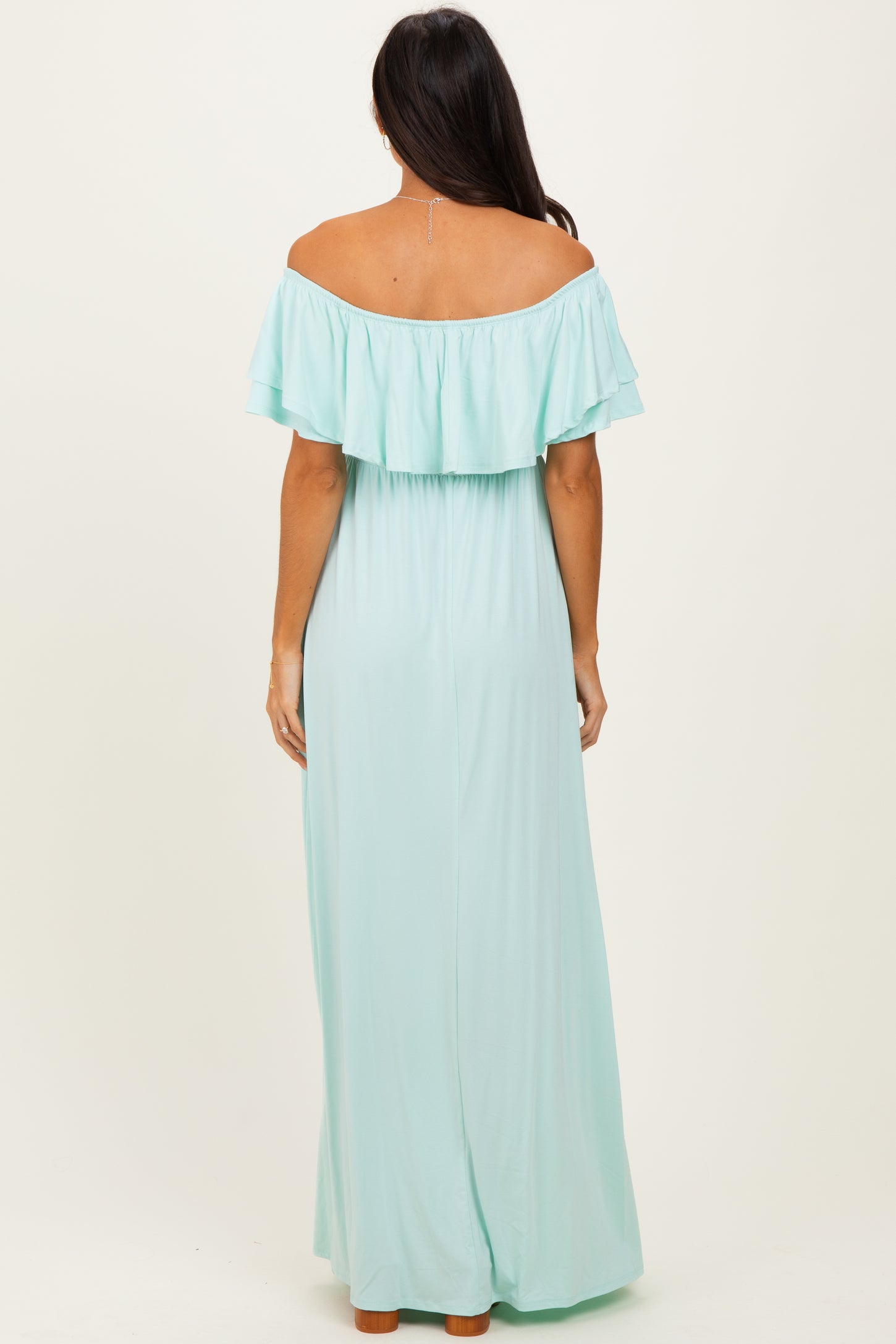 woman wearing a flowy off-the-shoulder mint green maxi dress, showing the back view and ruffled neckline