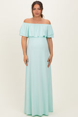 woman wearing a mint green off-the-shoulder maternity maxi dress with ruffle details and a visible baby bump