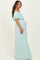 woman wearing a light mint green off-the-shoulder maternity maxi dress with ruffle details and showing her baby bump