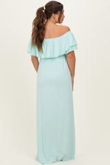 woman wearing a mint green off-the-shoulder maternity maxi dress with ruffle details and an elastic waistband