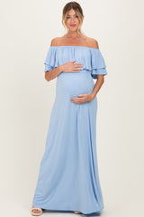 woman wearing a light blue off-the-shoulder maternity maxi dress and holding her baby bump