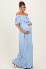 woman wearing a light blue off-the-shoulder maternity gown with ruffle details and holding her baby bump